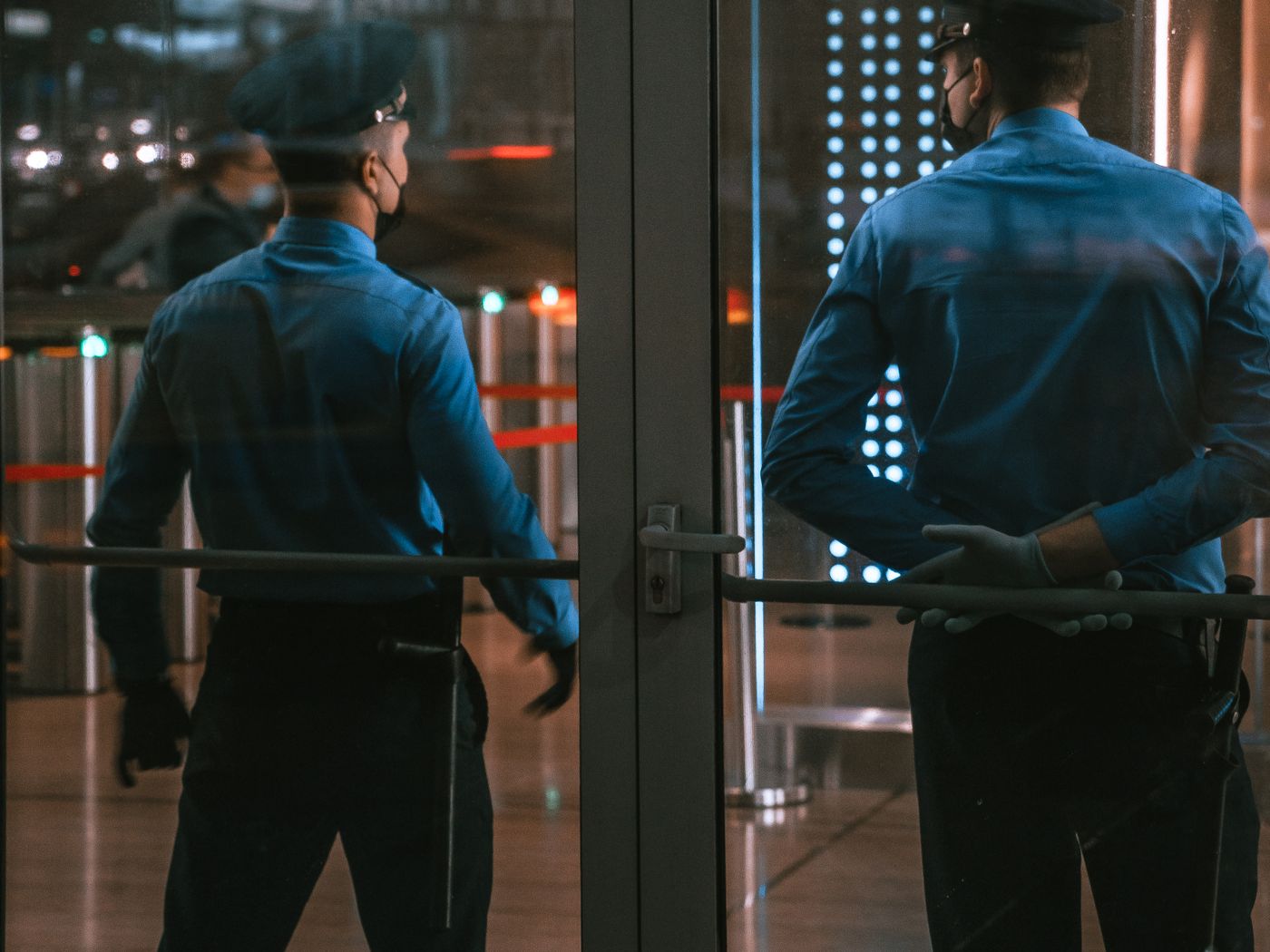 Two crowd controllers on duty at a lit venue entrance after dark